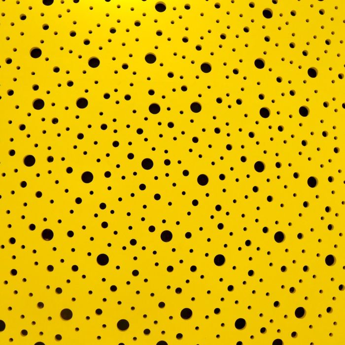 Black polka dots of different sizes against a yellow background.