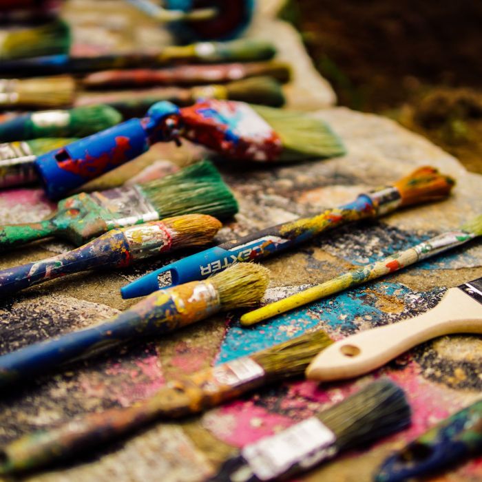 A photograph of several paintbrushes of different sizes covered in dried paint.