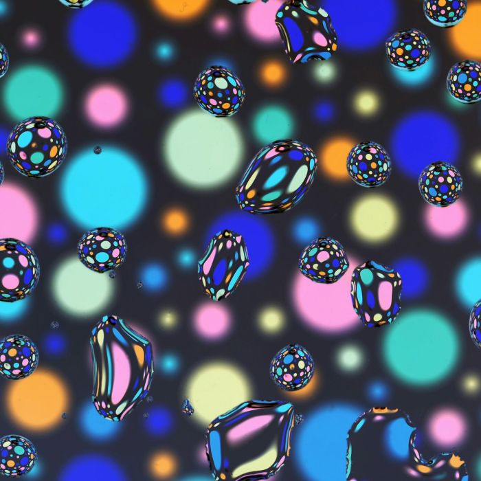colorful bubbles floating on a black background - Drops of a glycerine/water mixture working like magnifying glasses, on glass, above an abstract artwork.