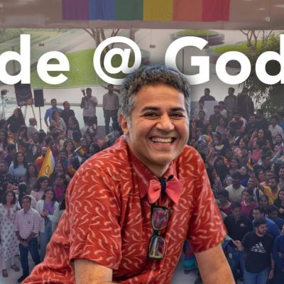 A photo of people celebrating pride in the background and a larger photo of Parmesh Shahani imposed over it in the centre. At the top, there is white text which says "Pride @ Godrej"