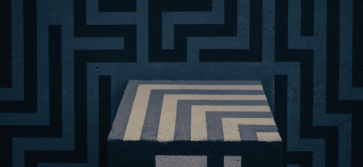 A cube placed against a flat, vertical plain surface. A maze pattern is superimposed over everything.