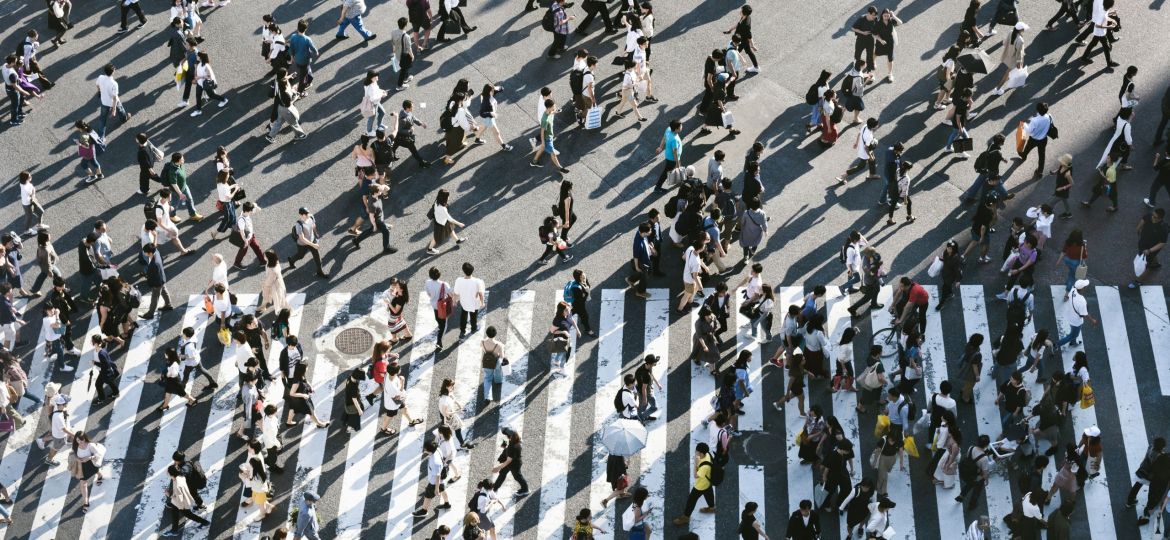 Aerial view of a lot of people walking on road across a zebra crossing.