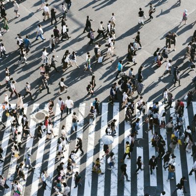 Aerial view of a lot of people walking on road across a zebra crossing.