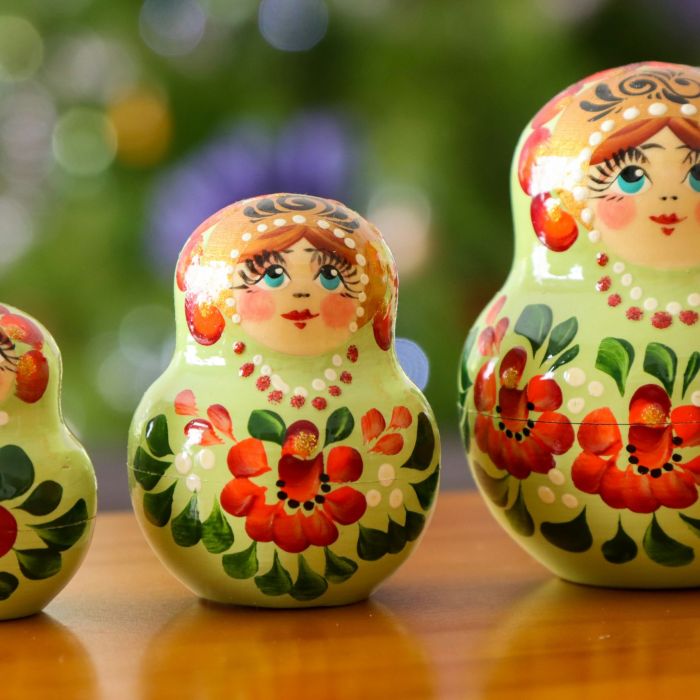 A group of three nesting dolls or matryoshka dolls sitting on top of a wooden table