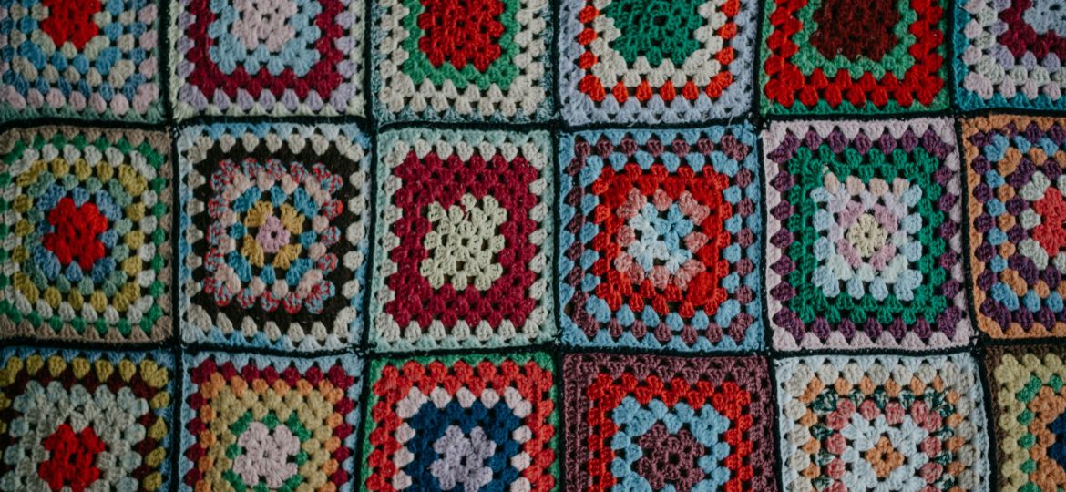 A close-up of a crocheted blanket formed of vibrant squares of knitted fabric.