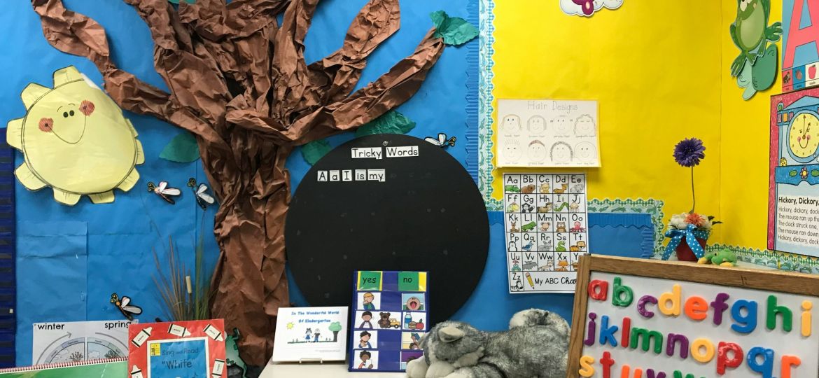 Assorted animal plush toys on white wooden shelf in a classroom setting which seems to be catered to young kids in a primary or elementary school.